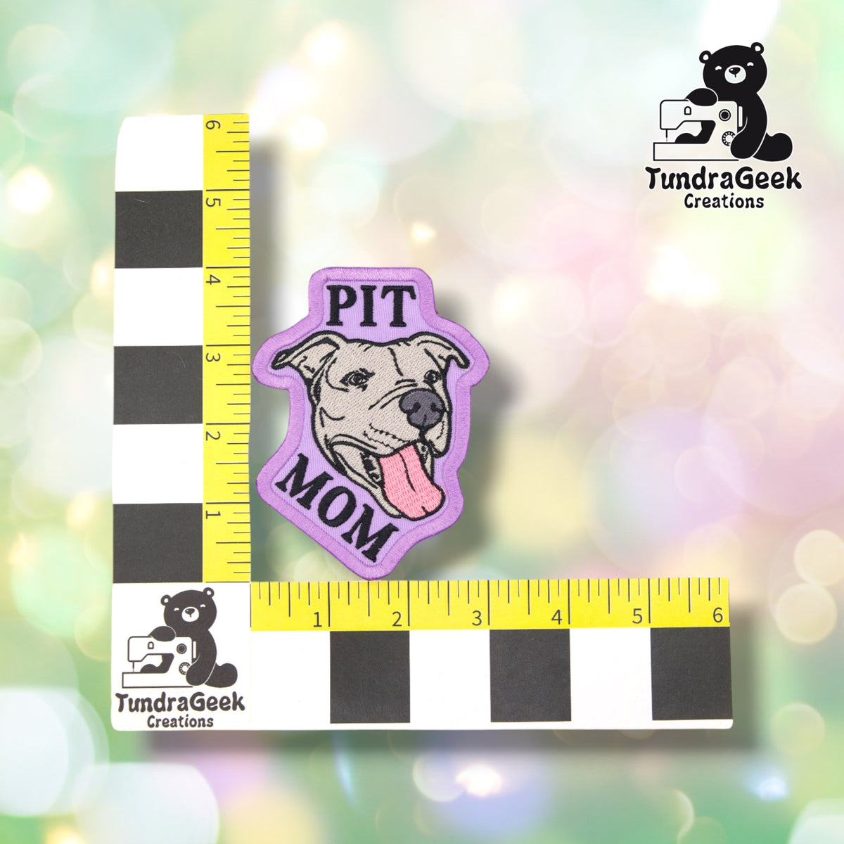 The Pit Mom patch photographed against a yellow ruler marked in inches along both edges, for size reference. It measures just under 4 inches tall by 3 inches wide.  ---