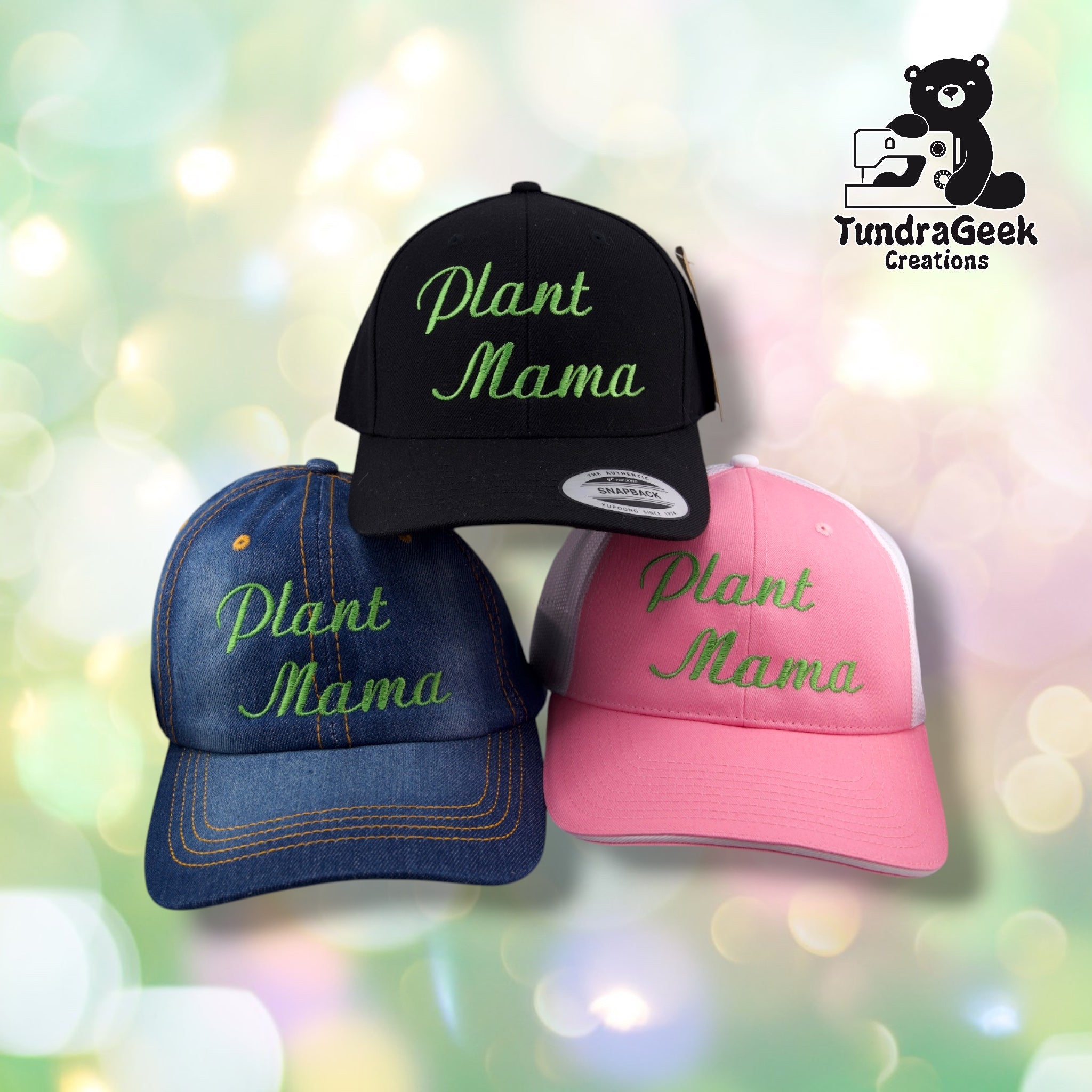 Three baseball caps in black, denim blue, and pink with green "Plant Mama" embroidery, displayed against a soft bokeh background with TundraGeek Creations logo.