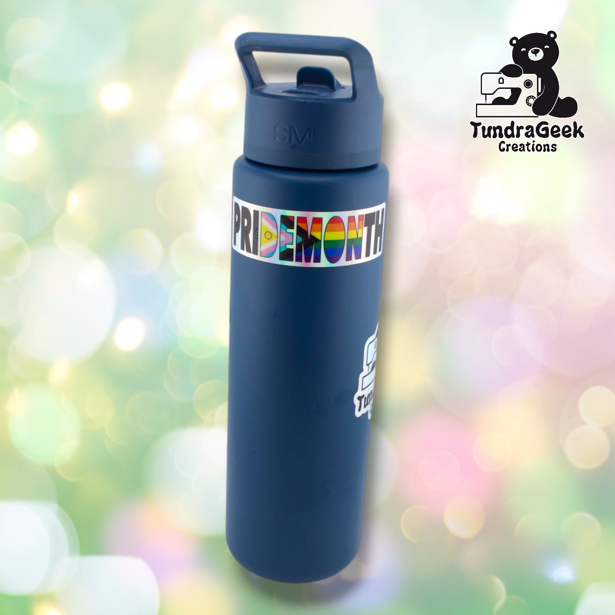 Pride Month holographic sticker applied to a navy blue insulated water bottle, wrapping around near the top. Sticker shown in context demonstrating real-world size and application.
