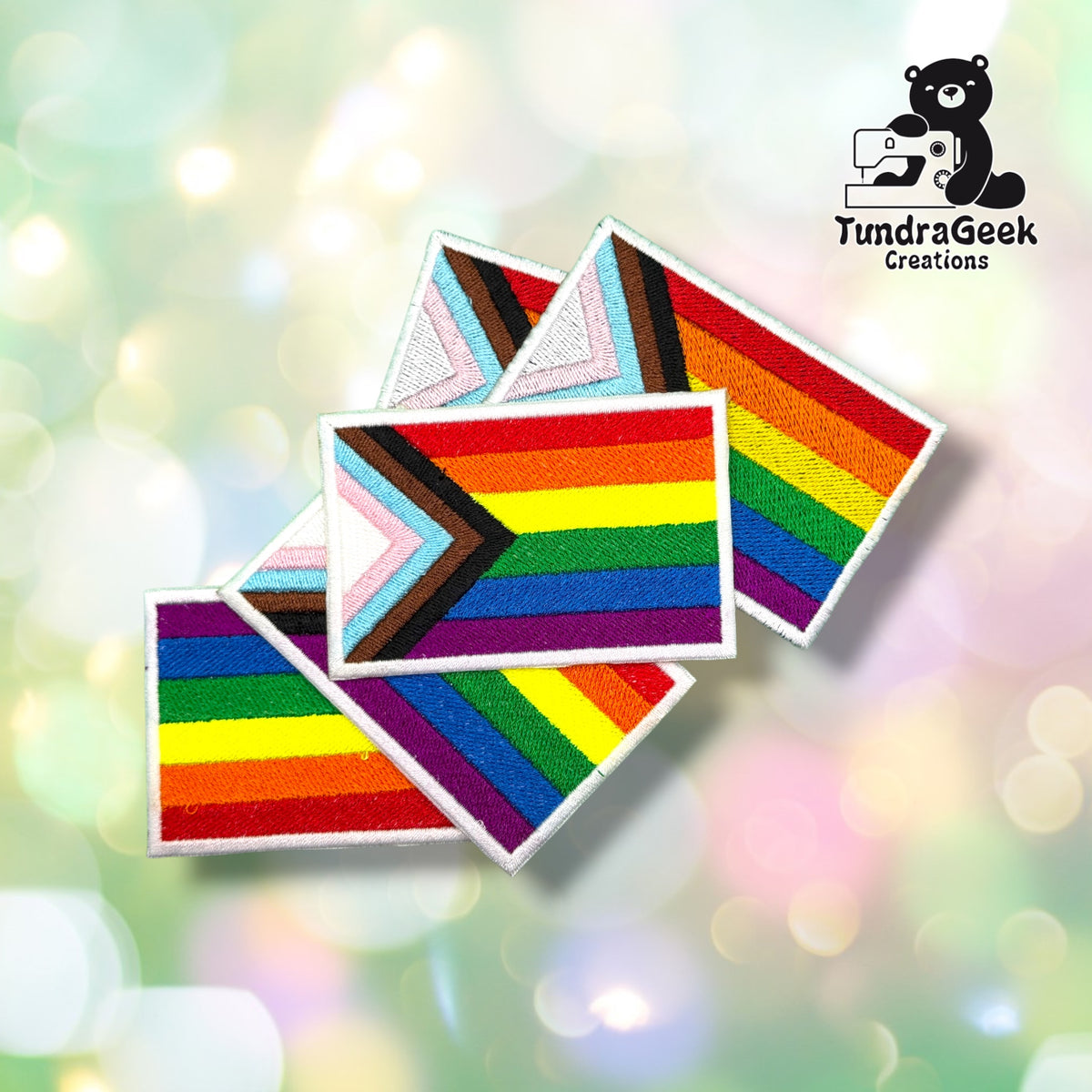 Four identical Progress Pride rectangular patches fanned out together, each showing the same chevron-and-rainbow design.