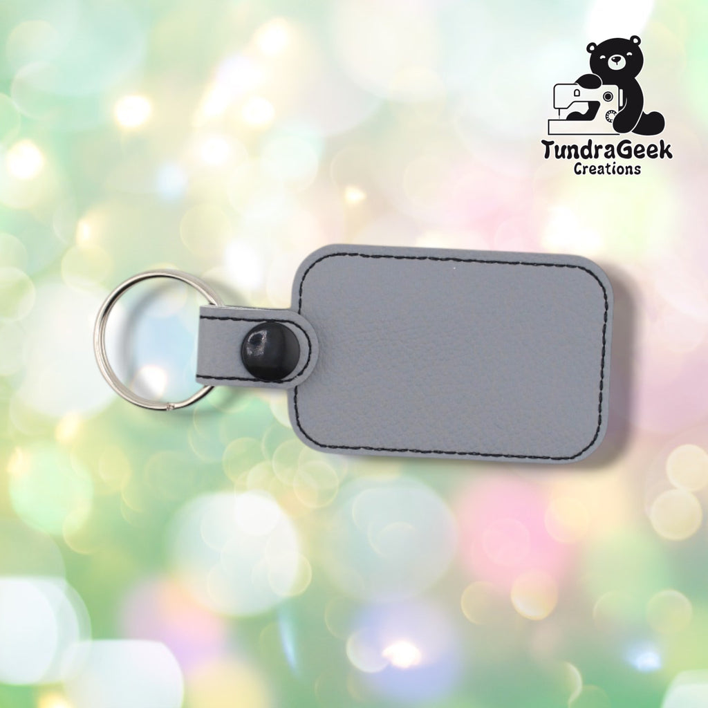 Back view of the keychain showing the plain gray vinyl backing and black plastic snap closure, no embroidery visible from this side.