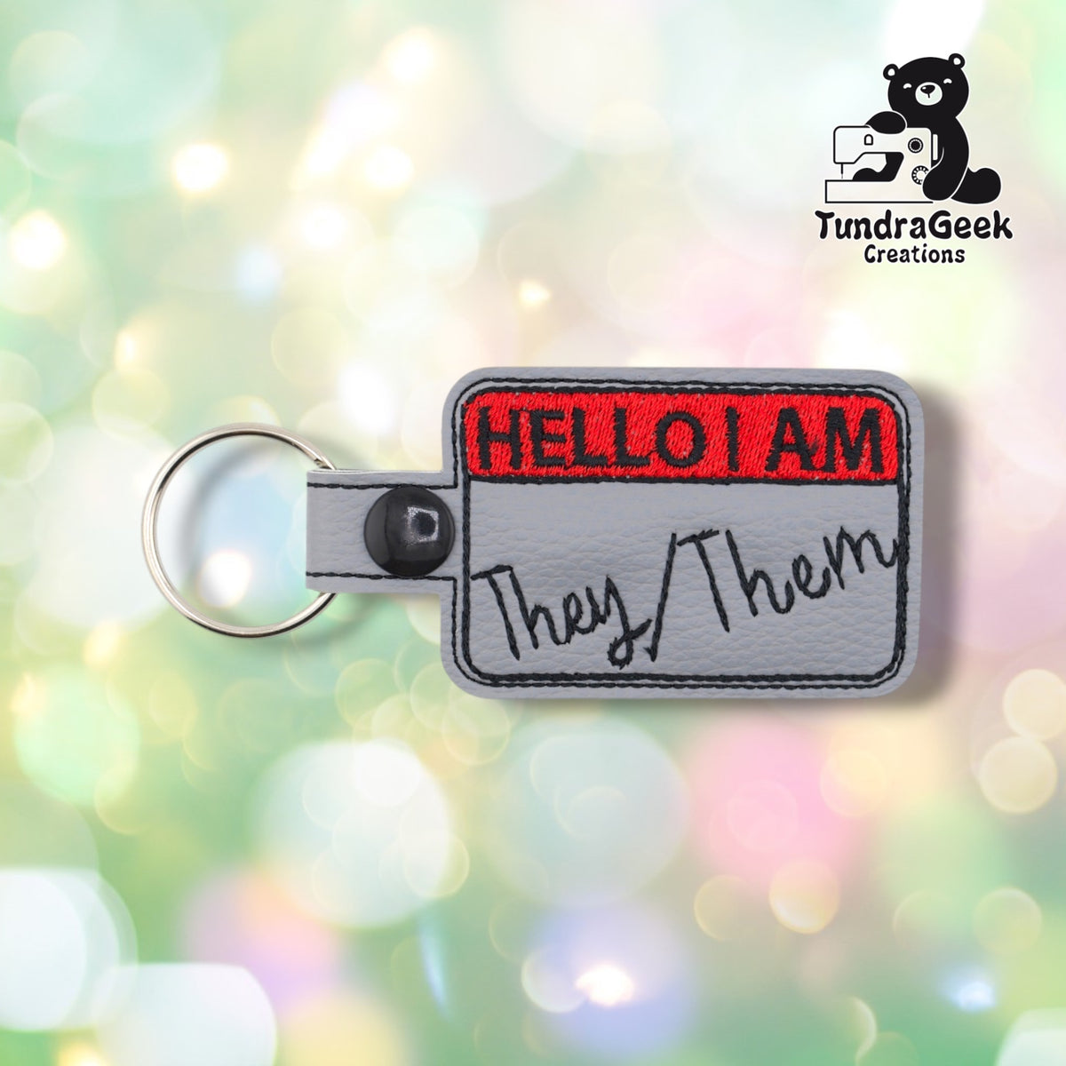 Front view with "They/Them" embroidered in black beneath the red "HELLO I AM" header.