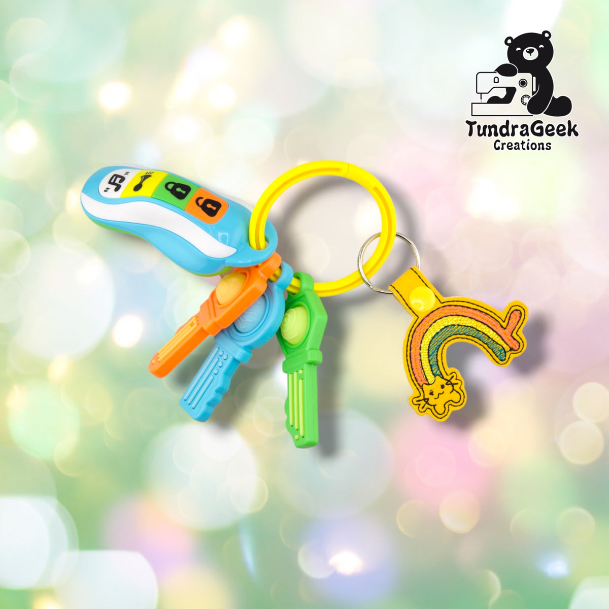 The keychain clipped to a yellow silicone bangle keyring alongside a set of colorful plastic toy keys, showing it in everyday use.