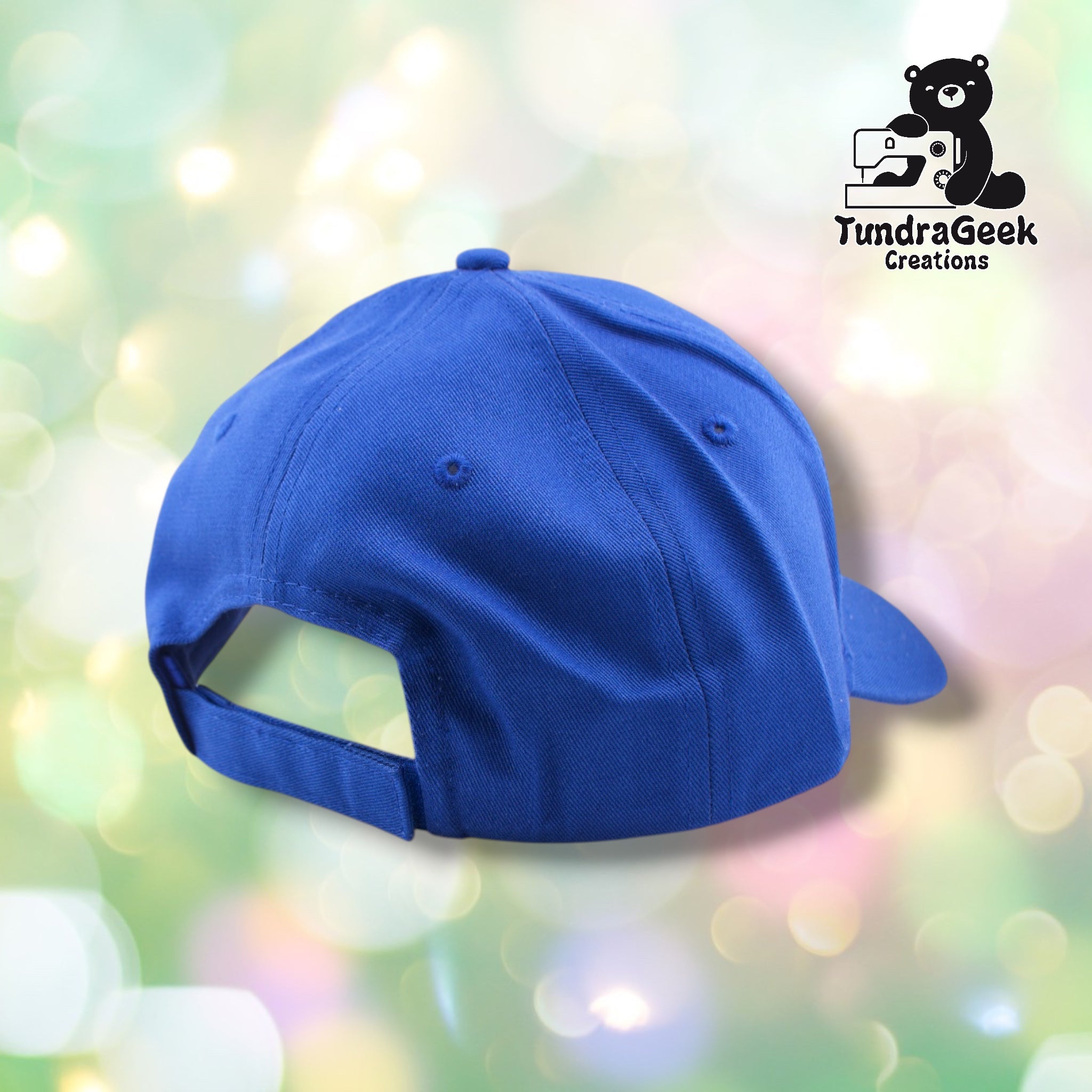 A bright blue baseball cap with adjustable back strap displayed against a soft, blurred pastel background with bokeh lighting.