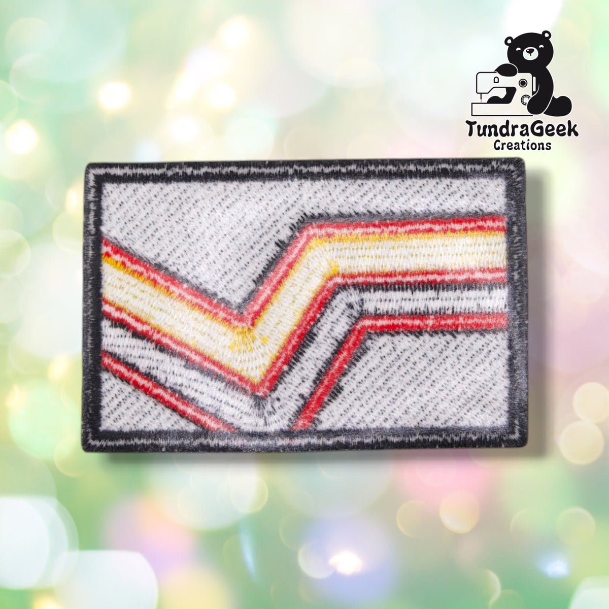 The back of the patch, showing the woven twill backing beneath the full-coverage embroidery, with the chevron pattern visible in reverse through the fabric.
