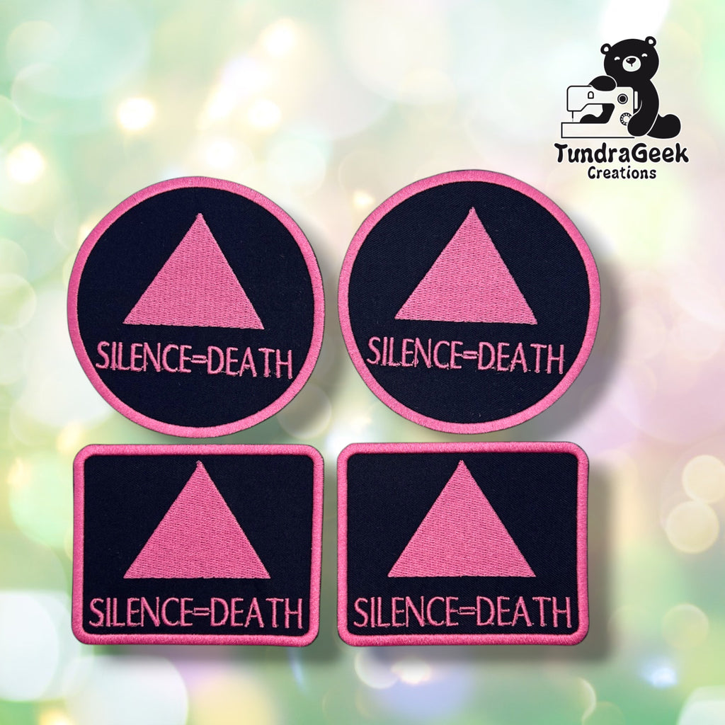 Four Silence=Death patches grouped together — two round and two rectangular — each showing a pink triangle above pink "SILENCE=DEATH" lettering on a black background with a pink merrowed edge.