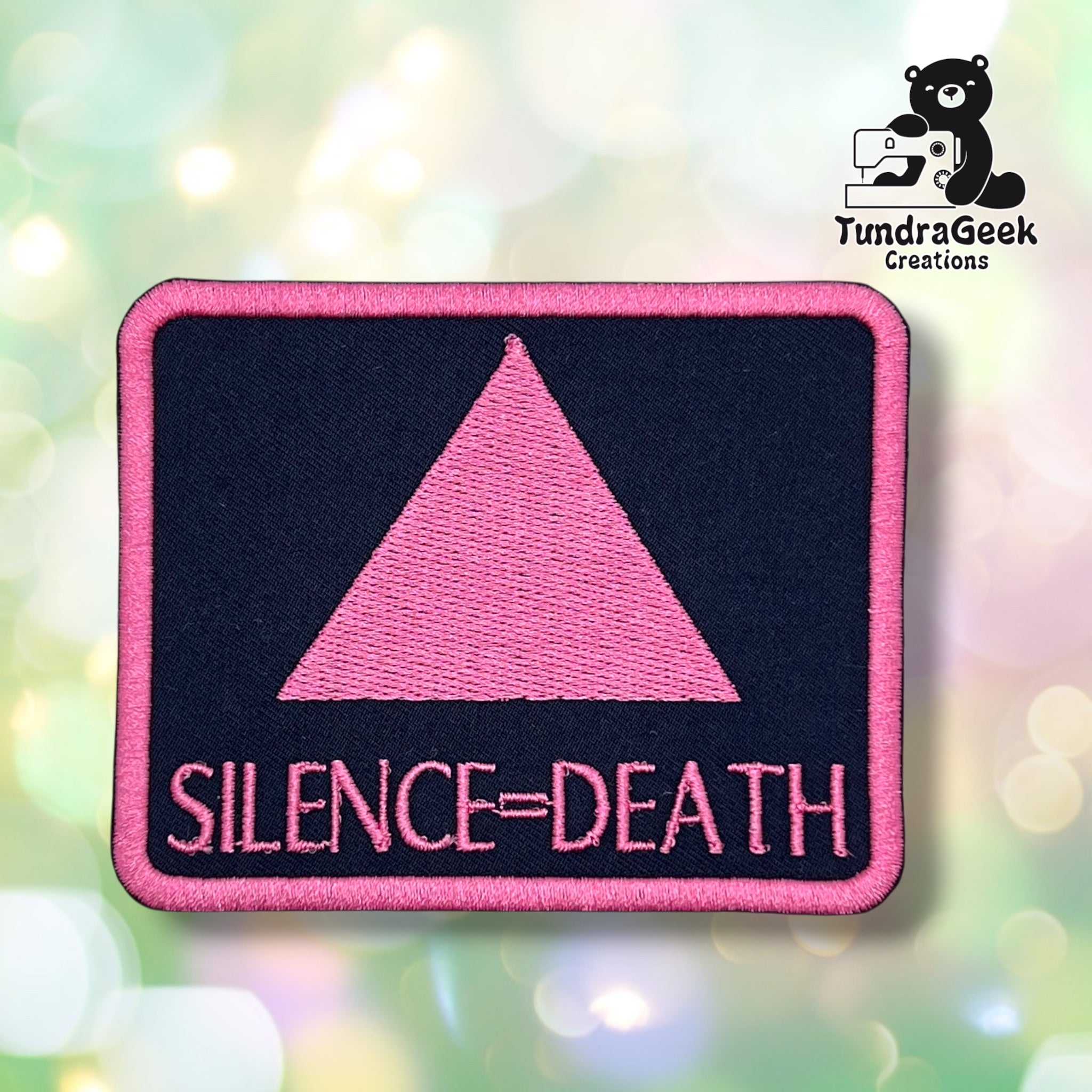 Front view of the rectangular variant: a black patch with a pink merrowed edge, embroidered with a solid pink triangle above "SILENCE=DEATH" in pink block lettering.