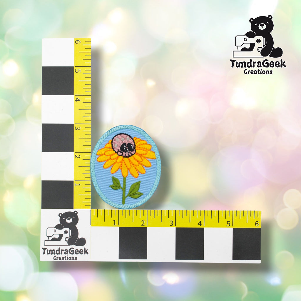 Skull flower patch positioned against a TundraGeek Creations branded ruler card showing yellow tape measure. Patch measures approximately 2.5 inches wide by 3 inches tall.