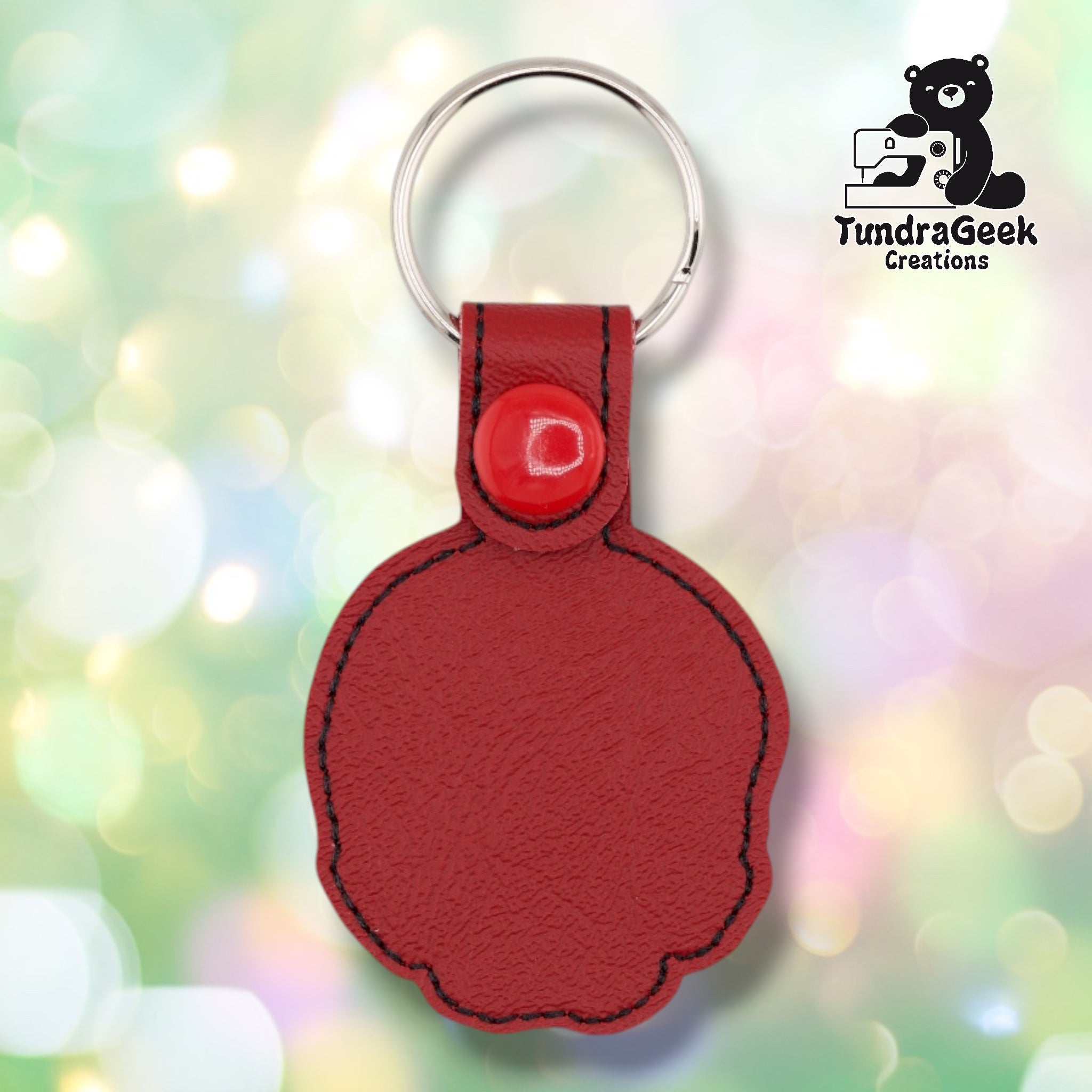 The back of the skull keychain, showing the plain red vinyl backing with black stitched edge detailing, the red plastic snap closure tab, and silver split ring. No embroidery on the reverse side.