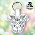 Embroidered keychain shaped like a dog’s face with decorative patterns, attached to a metal ring. TundraGeek Creations logo is visible in the upper right corner.