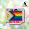 Front view of a rectangular patch with a white merrowed edge and gray background. "THESE COLORS" is embroidered in rainbow-colored letters across the top, above a Progress Pride flag (yellow, white, pink, light blue, brown, black chevron with a purple intersex circle, joined to a six-color rainbow field). "DON'T RUN" is embroidered in red block letters below.