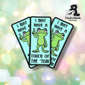 Three of the same patch fanned out and overlapping, each showing the teal background, green frog raising one finger, and the full "I MAY HAVE A TOUCH OF THE 'TISM" text.