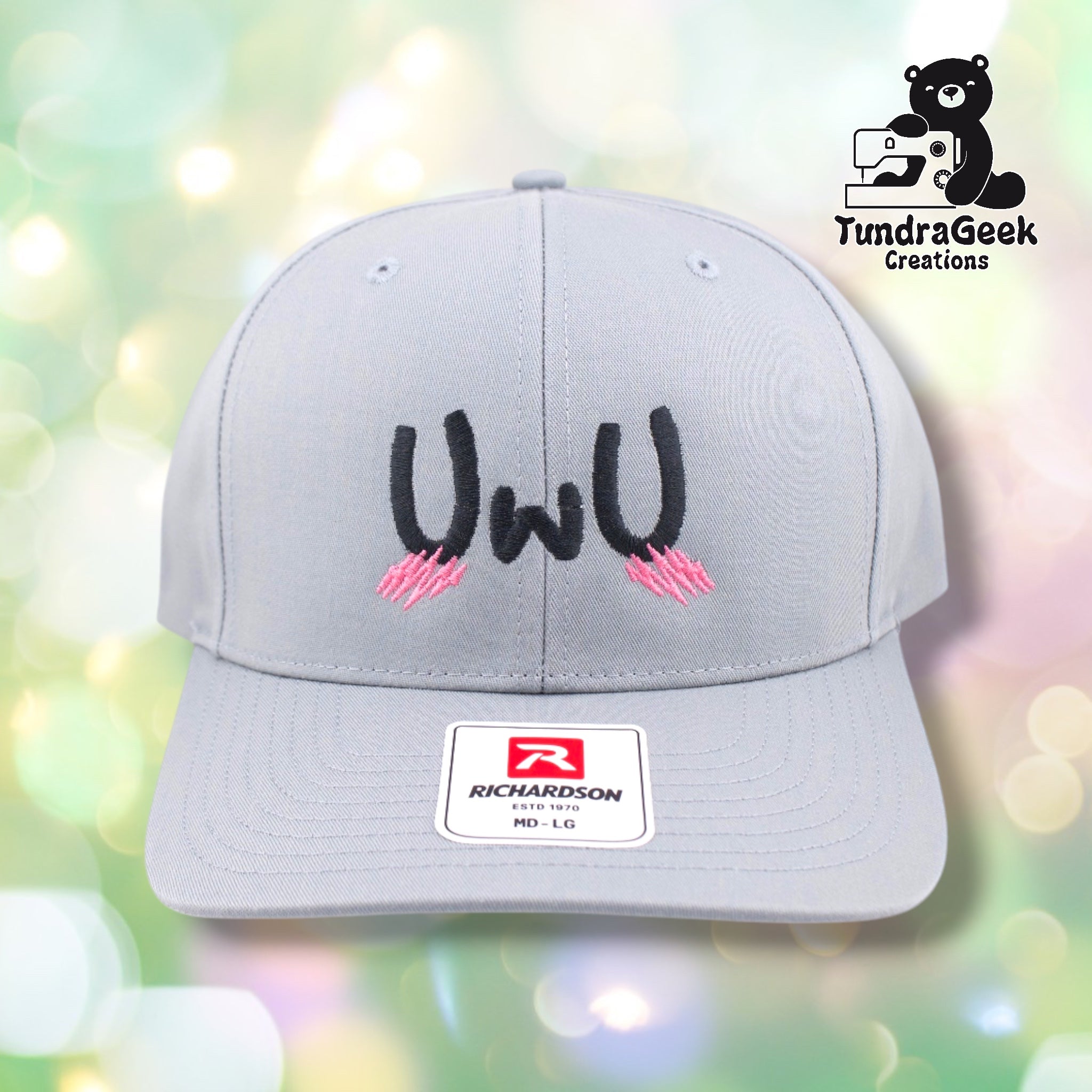 A light gray Richardson baseball cap with black and pink embroidered eyes design and Richardson brand label on the front.