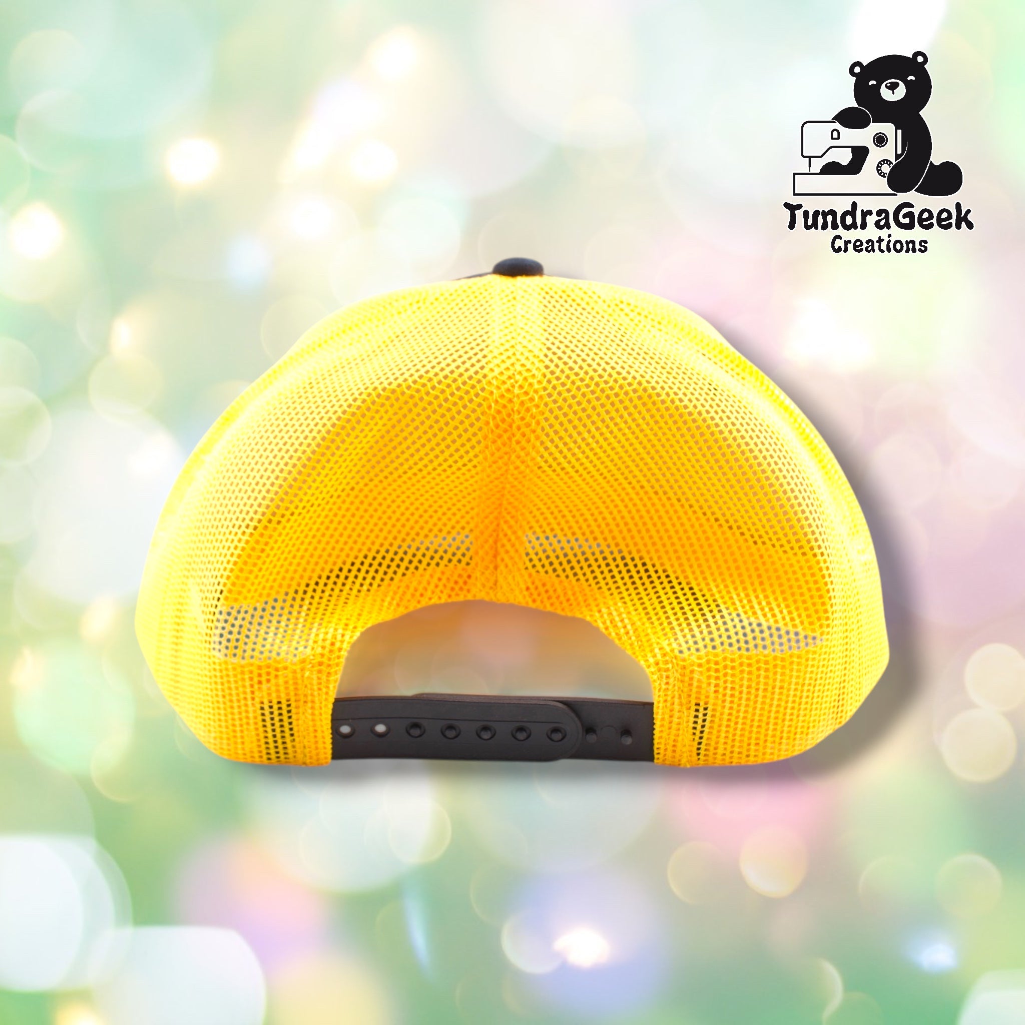 A bright yellow mesh trucker cap with black snap closure back strap displayed against a soft, blurred pastel background.