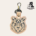 Tan leather keychain with an embroidered geometric tiger face design, metal clasp, and “TundraGeek Creations” logo featuring a bear with a sewing machine in the corner.