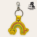 Yellow keychain with an embroidered rainbow and cat face, attached to a metal ring and clip. TundraGeek Creations logo with a bear and sewing machine is in the top right corner.