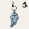 Light blue embroidered keychain featuring a cartoon otter with a smiling face, attached to a metal keyring and clasp. TundraGeek Creations logo is visible in the top right corner.