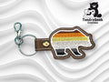 Embroidered bear keychain with brown, orange, yellow, and white stripes on a wavy white background, next to TundraGeek Creations logo.