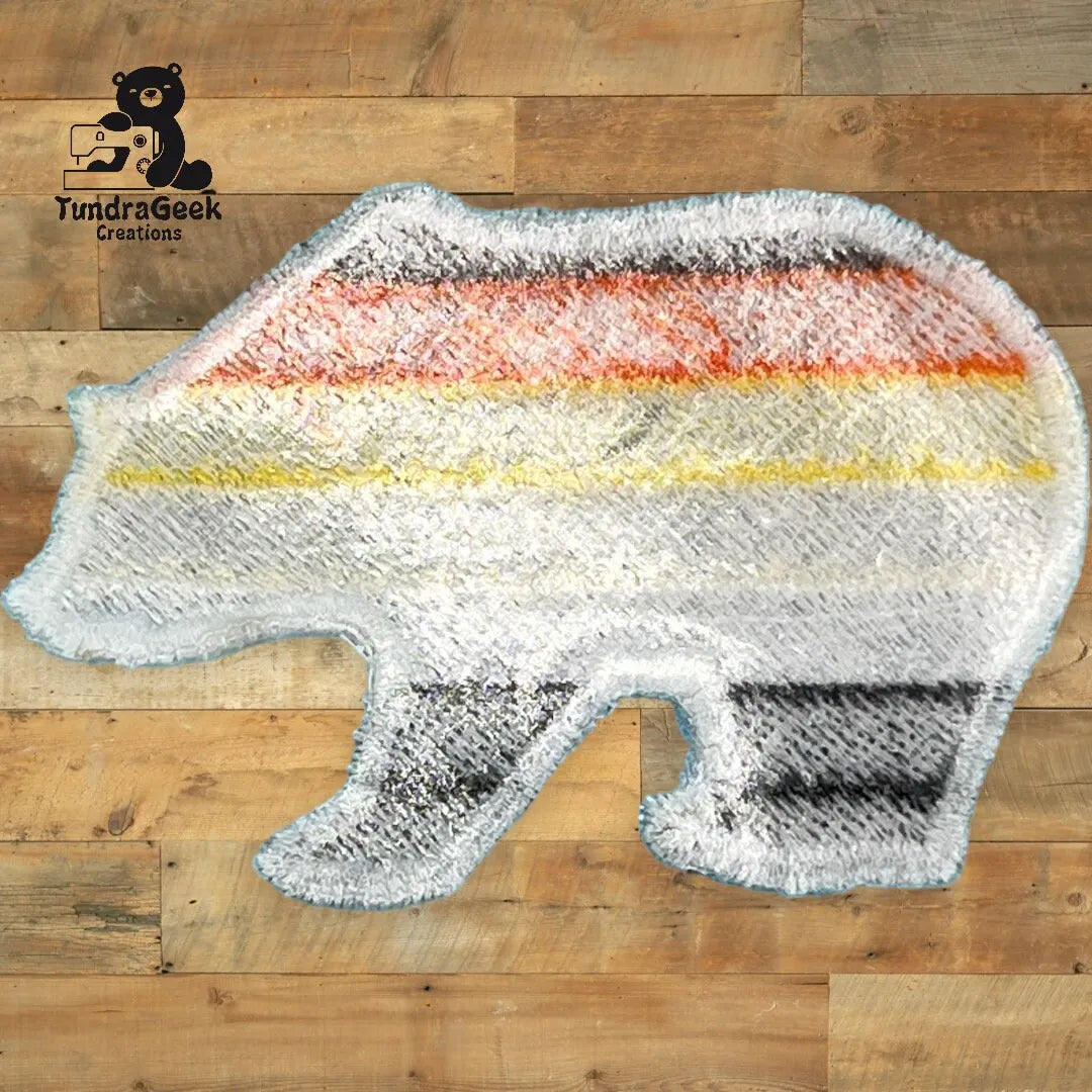 A bear-shaped rug with horizontal stripes in orange, yellow, black, and gray on a wooden floor, with the TundraGeek Creations logo in the top left corner.