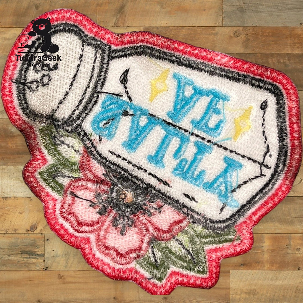 A decorative rug shaped like a tipped-over salt shaker with VITAL written in blue and surrounded by flowers, lying on a wooden floor.