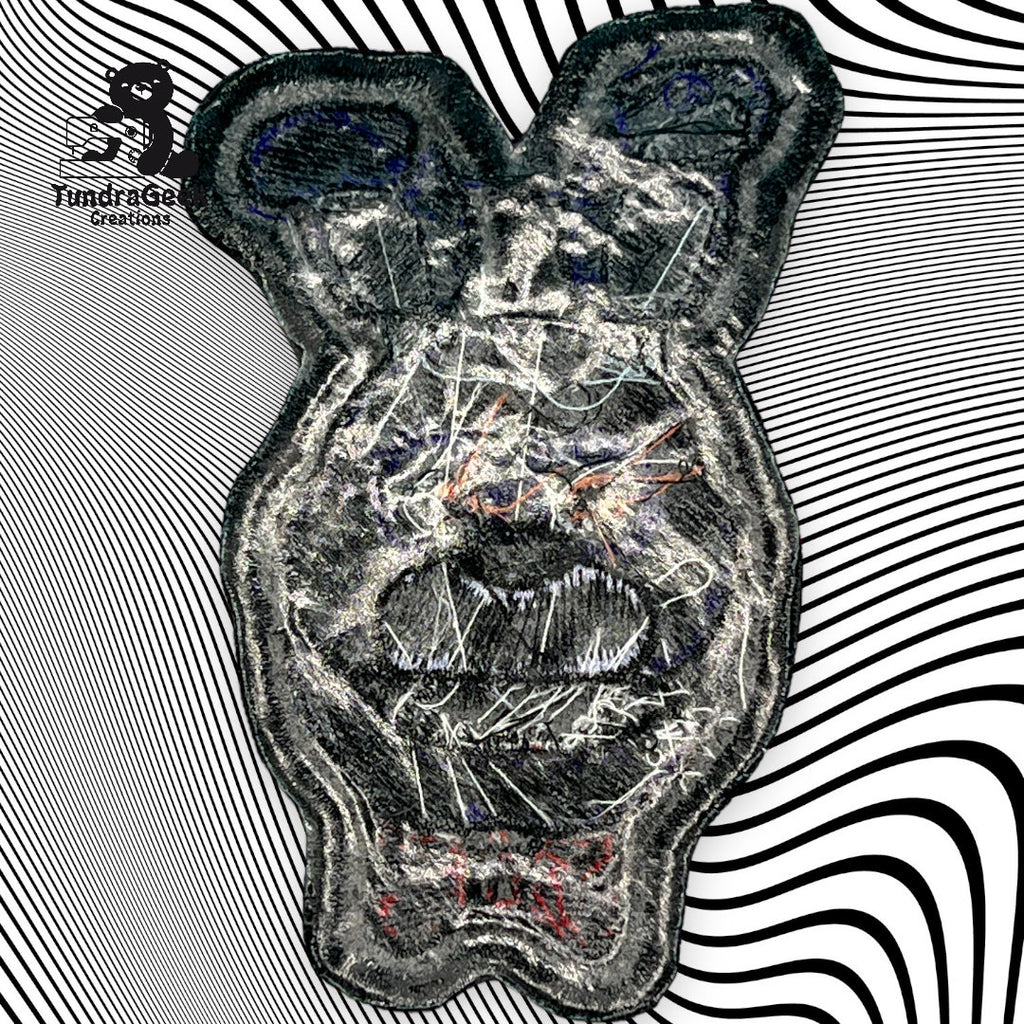 A textured, abstract bear face patch with scribbled details on a black and white wavy striped background, with the TundraGee Creations logo in the top left corner.