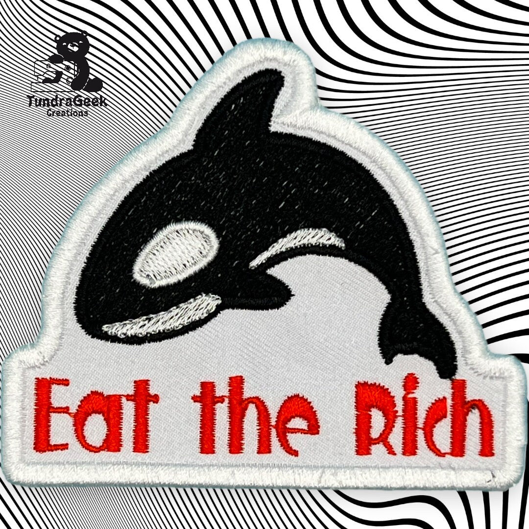 Embroidered patch of an orca with the text Eat the Rich in red, set against a black and white swirling background.
