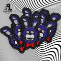 Several embroidered patches of a blue cartoon rabbit with red bow tie are arranged on a black and white optical illusion background.