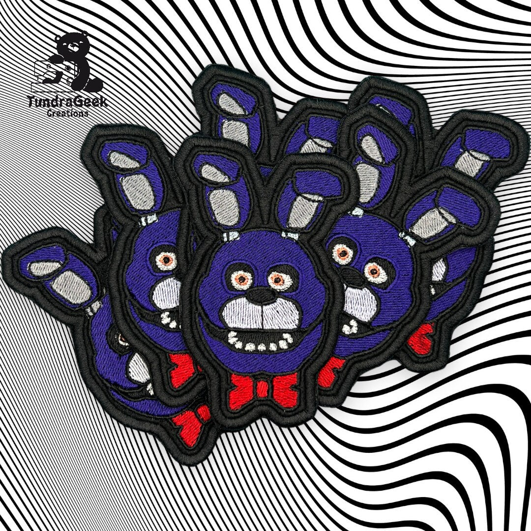 Several embroidered patches of a blue cartoon rabbit with red bow tie are arranged on a black and white optical illusion background.