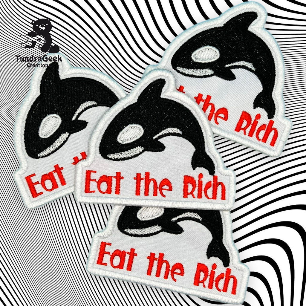 Four embroidered patches featuring an orca and the phrase Eat the Rich in red text, displayed on a black and white wavy background.
