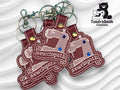 Four maroon keychains shaped like sewing machines with Sewciopath embroidered on each, displayed on a white textured background with a TundraGeek Creations bear logo.