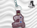 Keychain shaped like a sewing machine with the word sewciopath embroidered on it, displayed on a textured white background; TundraGeek Creations logo in the top right corner.