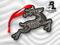A black embroidered ornament shaped like a reindeer with skeletal details, featuring a red ribbon and the TundraGeek Creations logo in the top right corner.