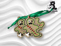 Two gingerbread-shaped ornaments with stitched details and green ribbons, featuring one large eye, red scar lines, and a distressed expression, on a textured white background.