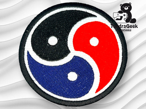 A circular embroidered patch featuring a tricolor yin-yang symbol in black, red, and blue, with the HydraGeek Creations logo in the top right corner.