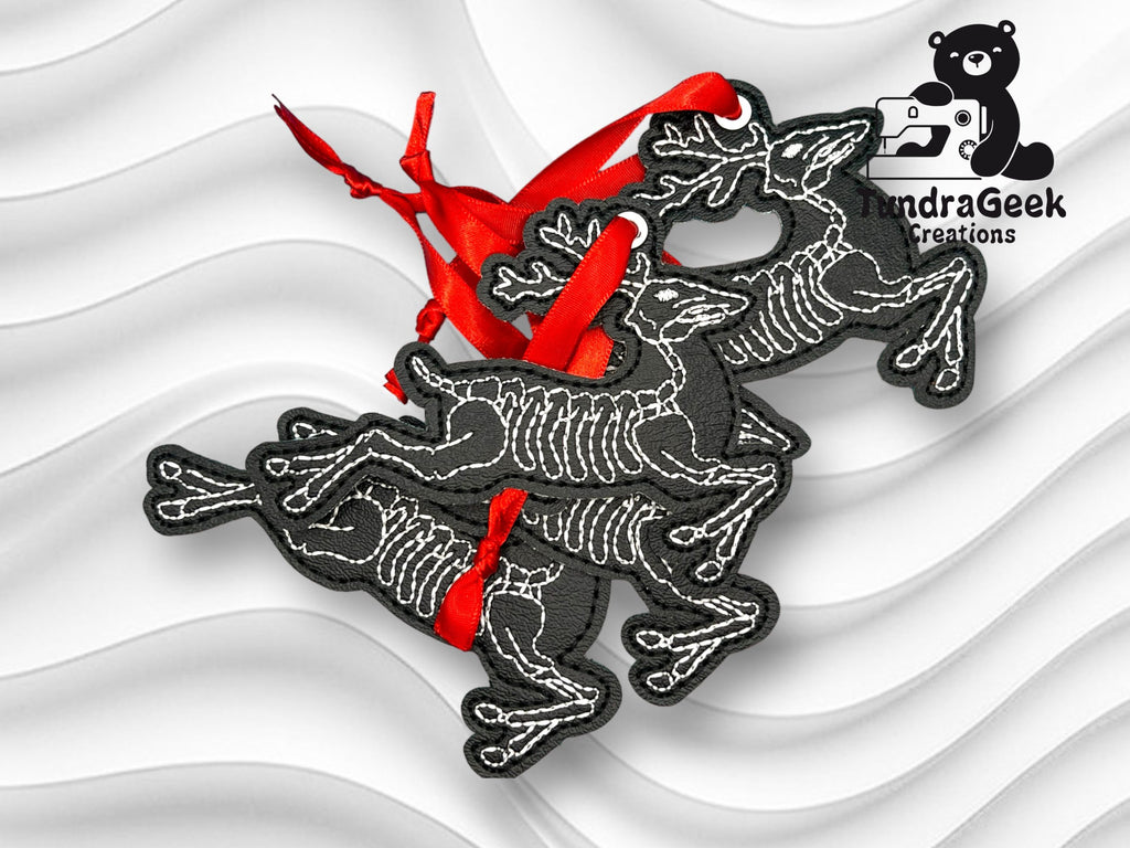 Three black skeletal reindeer ornaments with red ribbons are displayed on a white textured background, featuring the TundraGeek Creations logo.