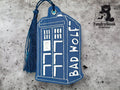 A blue, rectangular keychain shaped like the TARDIS from Doctor Who, embroidered with the words BAD WOLF and a blue tassel attached. TundraGeek Creations logo in the corner.