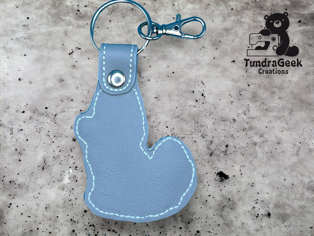 Light blue leather keychain in the shape of a squirrel, attached to a metal keyring and clasp, with the TundraGeek Creations logo in the background.