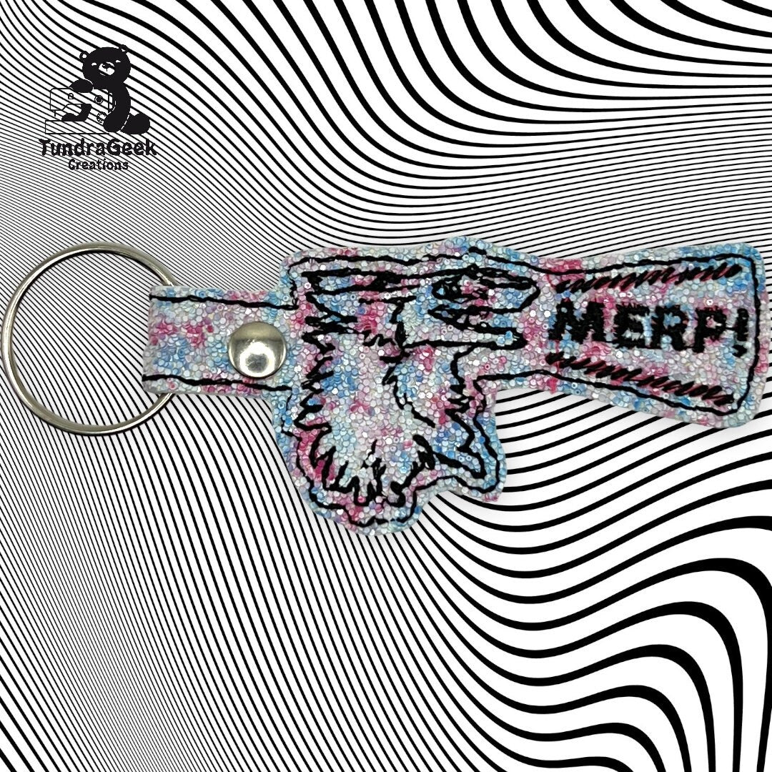 A glittery embroidered keychain shaped like a cartoon hand holding a gun with MERP! on it, displayed on a black-and-white wavy striped background.