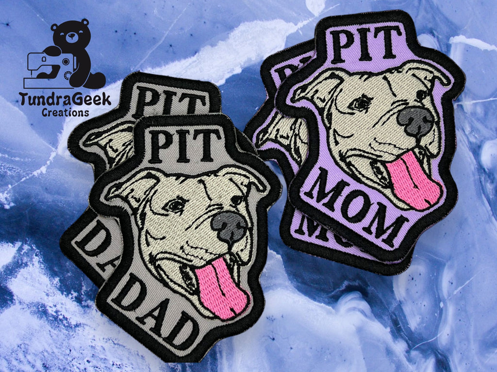Five embroidered patches featuring a pit bull’s face with “PIT DAD” and “PIT MOM” text, displayed on a marbled blue background with the TundraGeek Creations logo.