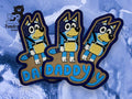 Three embroidered patches feature a cartoon blue dog with the word DADDY in blue text, placed on a blue and white background. Tundra Creative logo is in the top left corner.