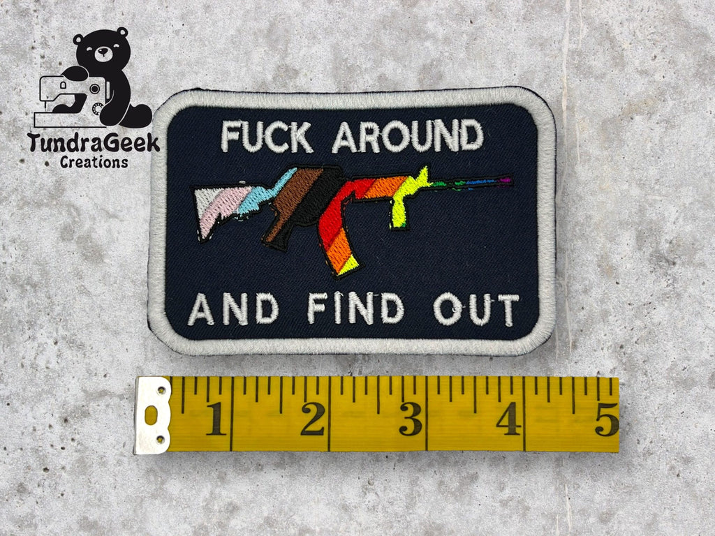 A rectangular patch with three rifles and the text FUCK AROUND AND FIND OUT, next to a yellow measuring tape showing a length of about 4 inches. TundraGeek Creations logo in the corner.