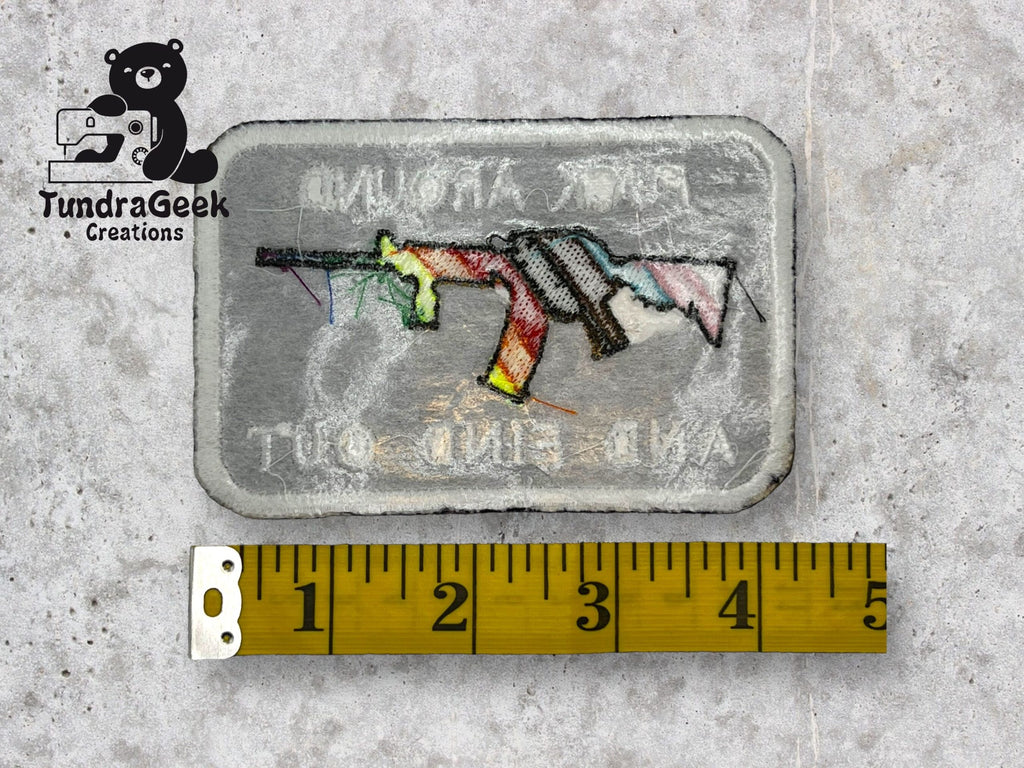 A rectangular embroidered patch with a colorful rifle design and faint text, next to a measuring tape showing about 3 inches. TundraGeek Creations logo is in the top left corner.