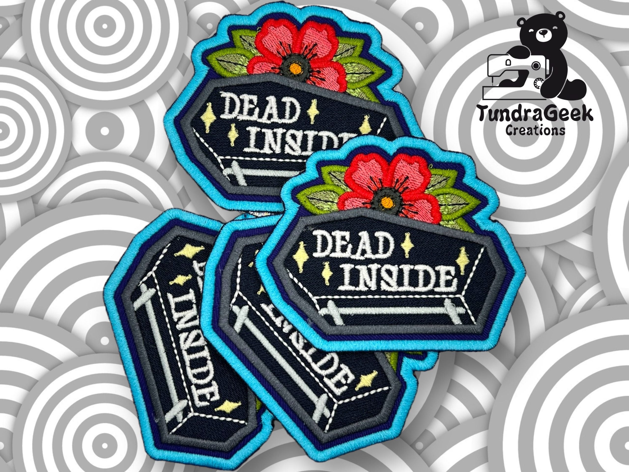 Embroidered patches with a coffin design, red flowers, and the text DEAD INSIDE are displayed on a patterned background with the TundraGeek Creations logo.