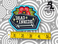 Embroidered patch with a coffin, flowers, and text DEAD INSIDE next to a yellow measuring tape on a patterned background. TundraGeek Creations logo in upper right corner.