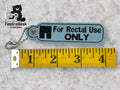 A keychain tag reading For Rectal Use ONLY next to a yellow measuring tape showing approximately 4 inches, with the TundraGeek Creations logo in the corner.