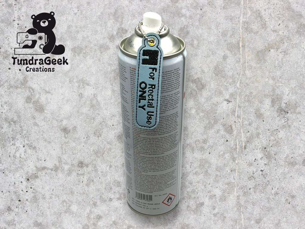 A spray can with a tag attached to the nozzle that reads For Recital Use Only stands upright on a light gray surface. The TundraGeek Creations logo appears in the top left corner.