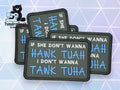 Four black rectangular patches with white and blue embroidered text read, IF SHE DONT WANNA HAWK TUAH I DONT WANNA TANK TUHA, arranged on a geometric background.