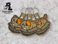 Three cat-in-box embroidered keychains displayed on a gray surface, with a black TundraGeek Creations logo in the top left corner.