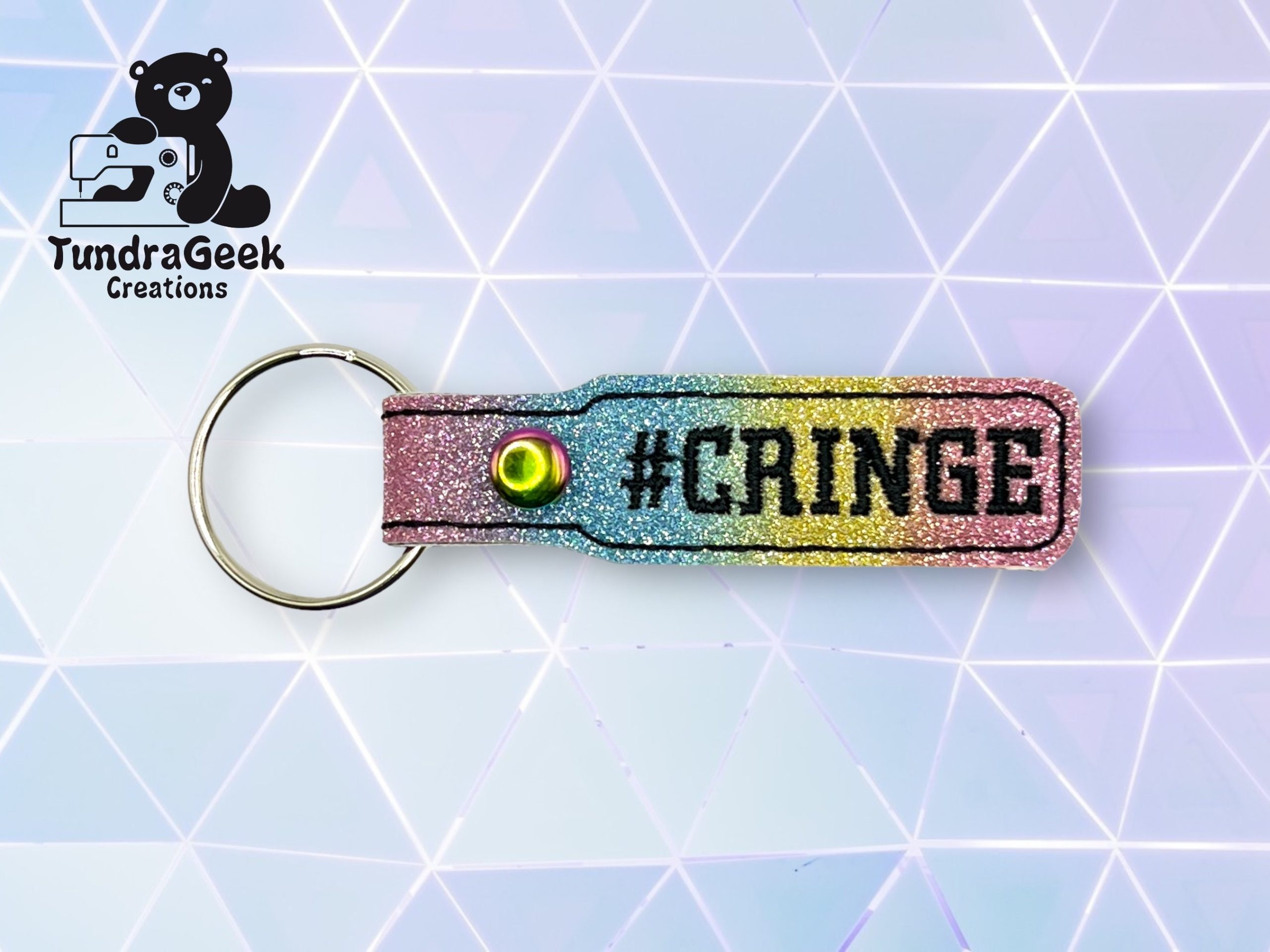 A glittery keychain with a metal ring displays the word #CRINGE in black text on a rainbow gradient background. The TundraGeek Creations logo is in the top left corner.