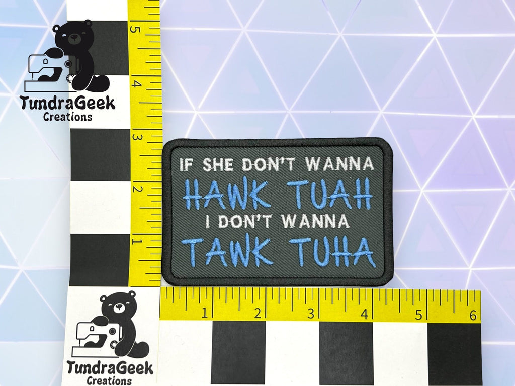 A rectangular patch reads IF SHE DONT WANNA HAWK TUAH I DONT WANNA TAWK TUHA in blue and white text, placed next to measuring rulers on a geometric background.